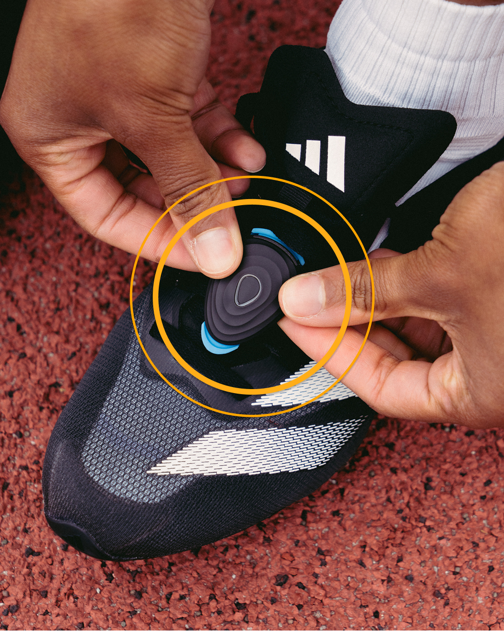 The Stryd Speed footpod being clipped onto a running shoe at the track